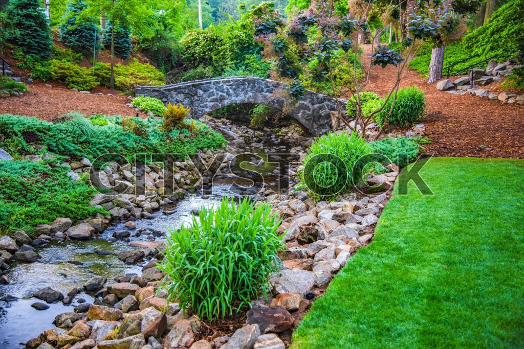 Stone bridge over a stream in a lush Greenville garden