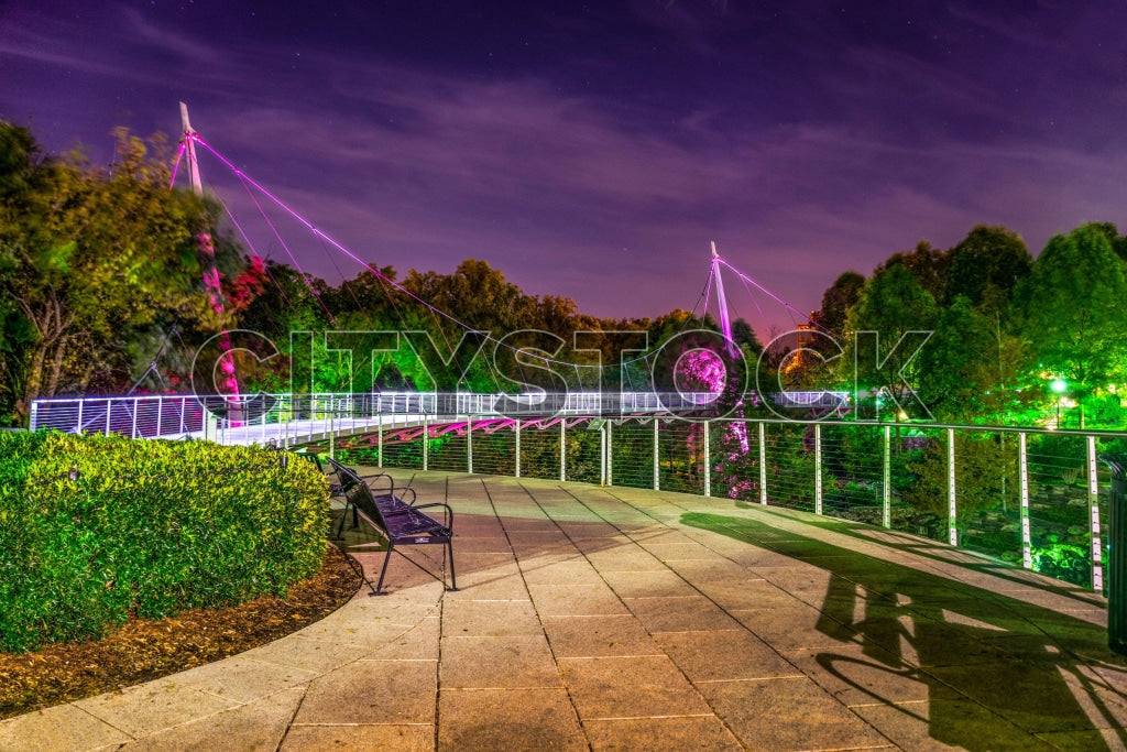 Illuminated bridge and bench in Greenville, SC at twilight