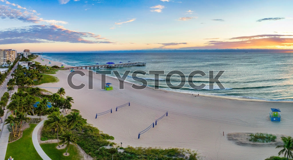 Early morning view of Pompano Beach, FL showing the beach and pier at sunrise.